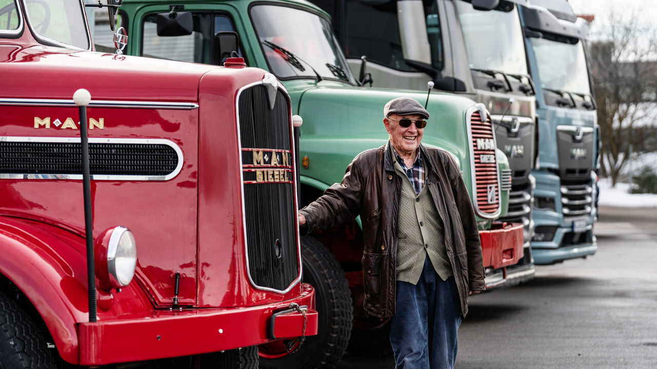 Kurt Bantle ist an einem MAN Oldtimer angelehnt und im Hintergrund sind 3 weitere MAN Lkw aus verschiedenen Jahrzehnten.