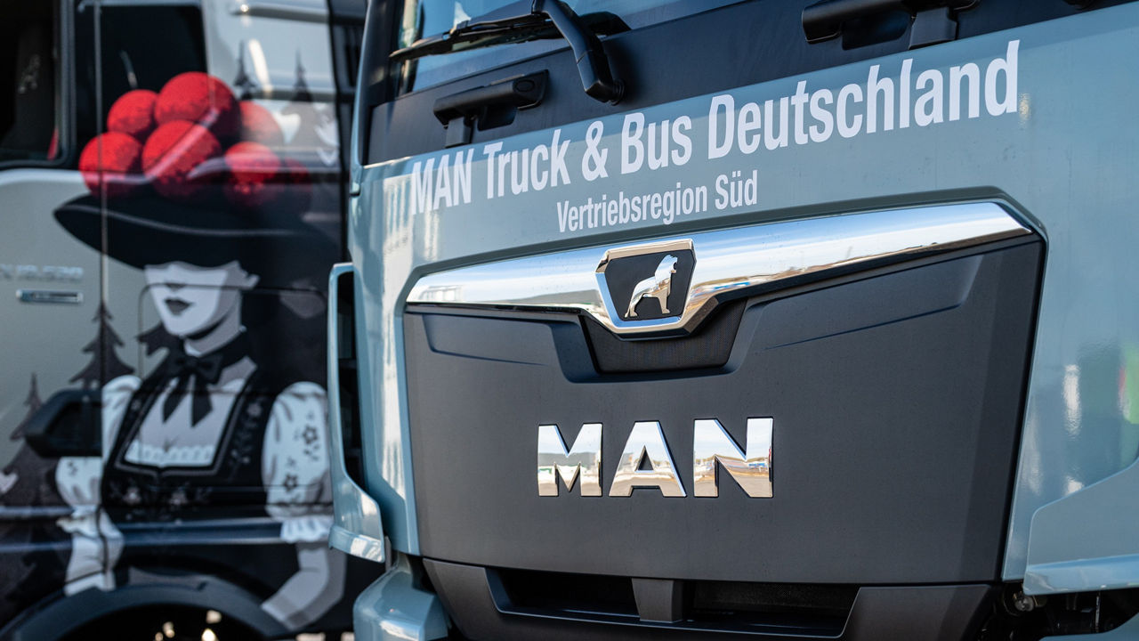 MAN TGX mit besonderen Airbrush und ein MAN eTGX nebeneinander vor dem MAN Servicebetieb.