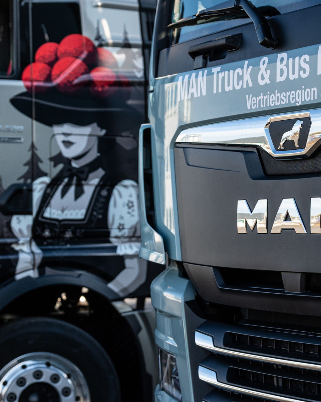 MAN TGX mit besonderen Airbrush und ein MAN eTGX nebeneinander vor dem MAN Servicebetieb.