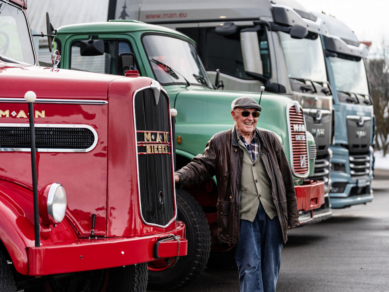 Kurt Bantle ist an einem MAN Oldtimer angelehnt und im Hintergrund sind 3 weitere MAN Lkw aus verschiedenen Jahrzehnten.