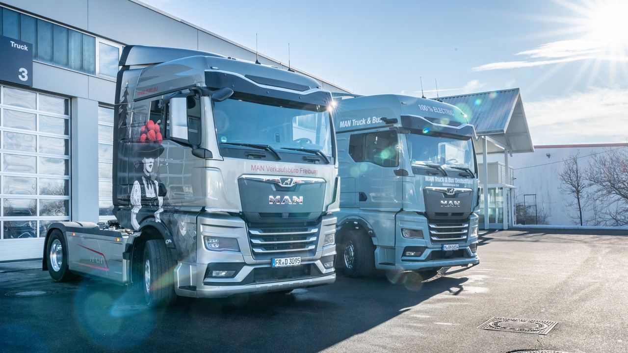 MAN TGX mit besonderen Airbrush und ein MAN eTGX nebeneinander vor dem MAN Servicebetieb.