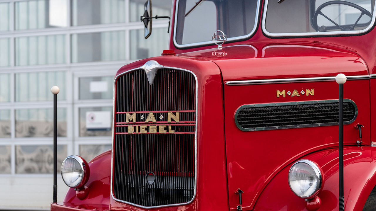 Kurt Bantle sitzt in einem roten Hauber MAN Oldtimer.
