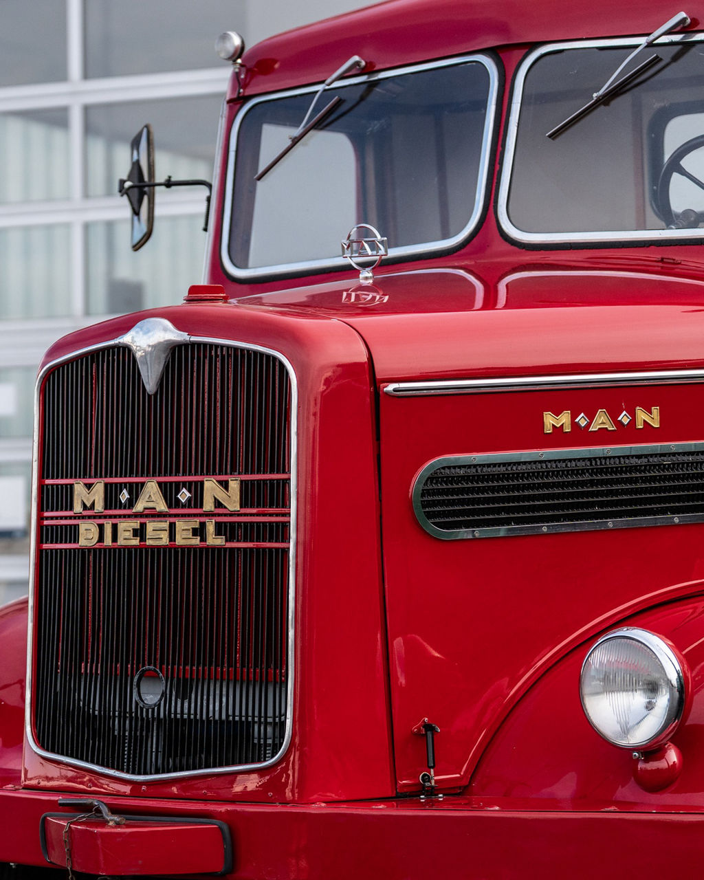 Kurt Bantle sitzt in einem roten Hauber MAN Oldtimer.