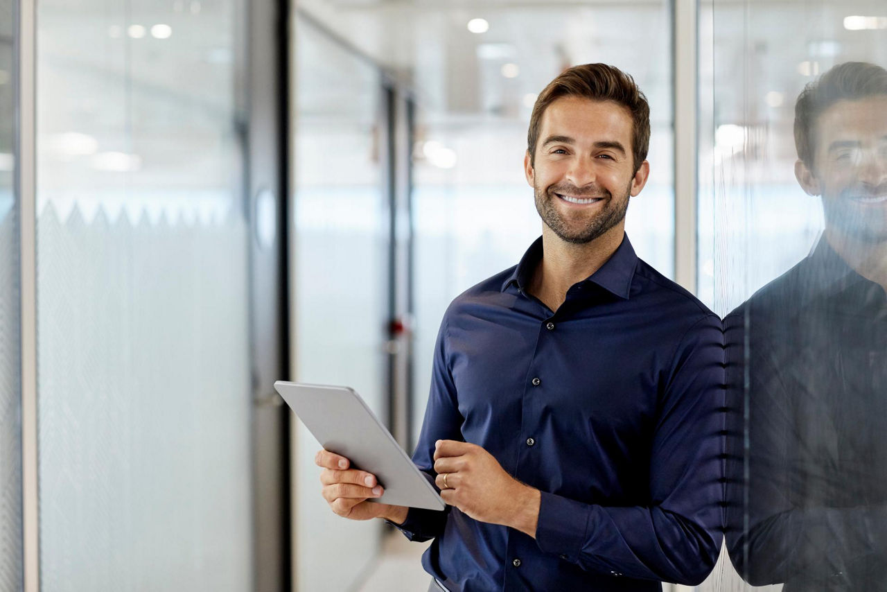 Lächelnder Mann mit Tablet in einem hellen Büro