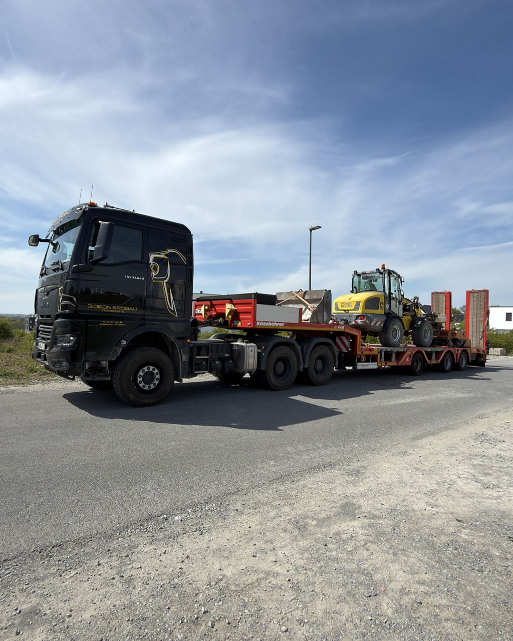Der schwarze MAN TGX 33.640 transportiert einen Radlader zur nächsten Baustelle.