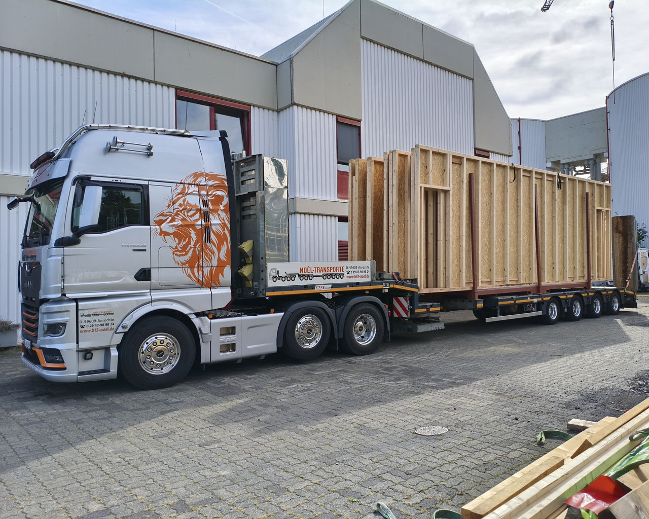 Der silberne MAN TGX transportiert Holzbauteile für ein Haus. 