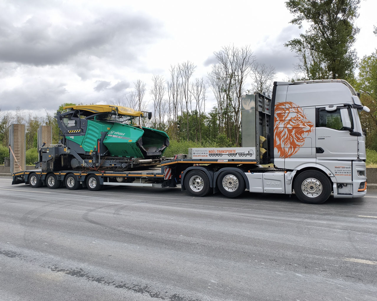 Die drei MAN TGX beliefern eine Autobahnbaustelle und transportieren einen Fertiger für den neuen Belag. 