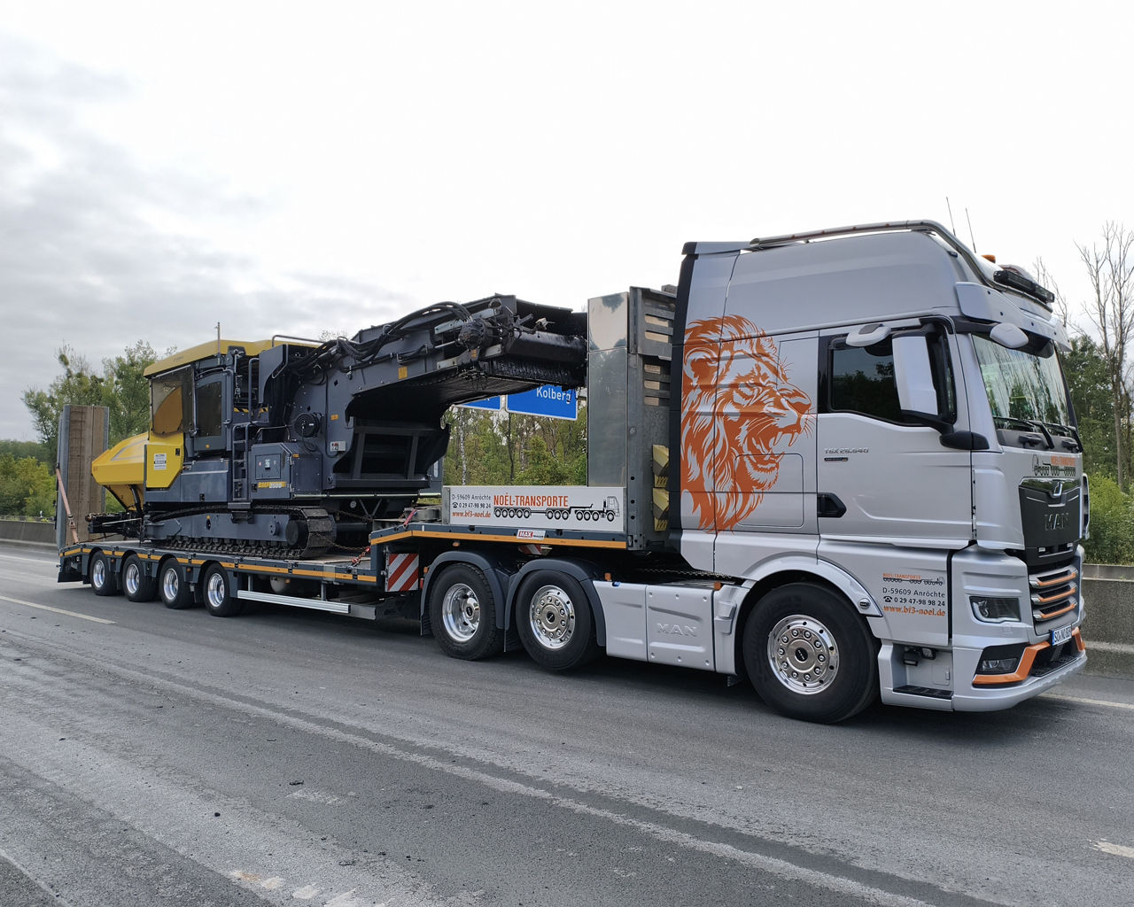 Die drei MAN TGX beliefern eine Autobahnbaustelle und transportieren eine Fräse für den Belag. 