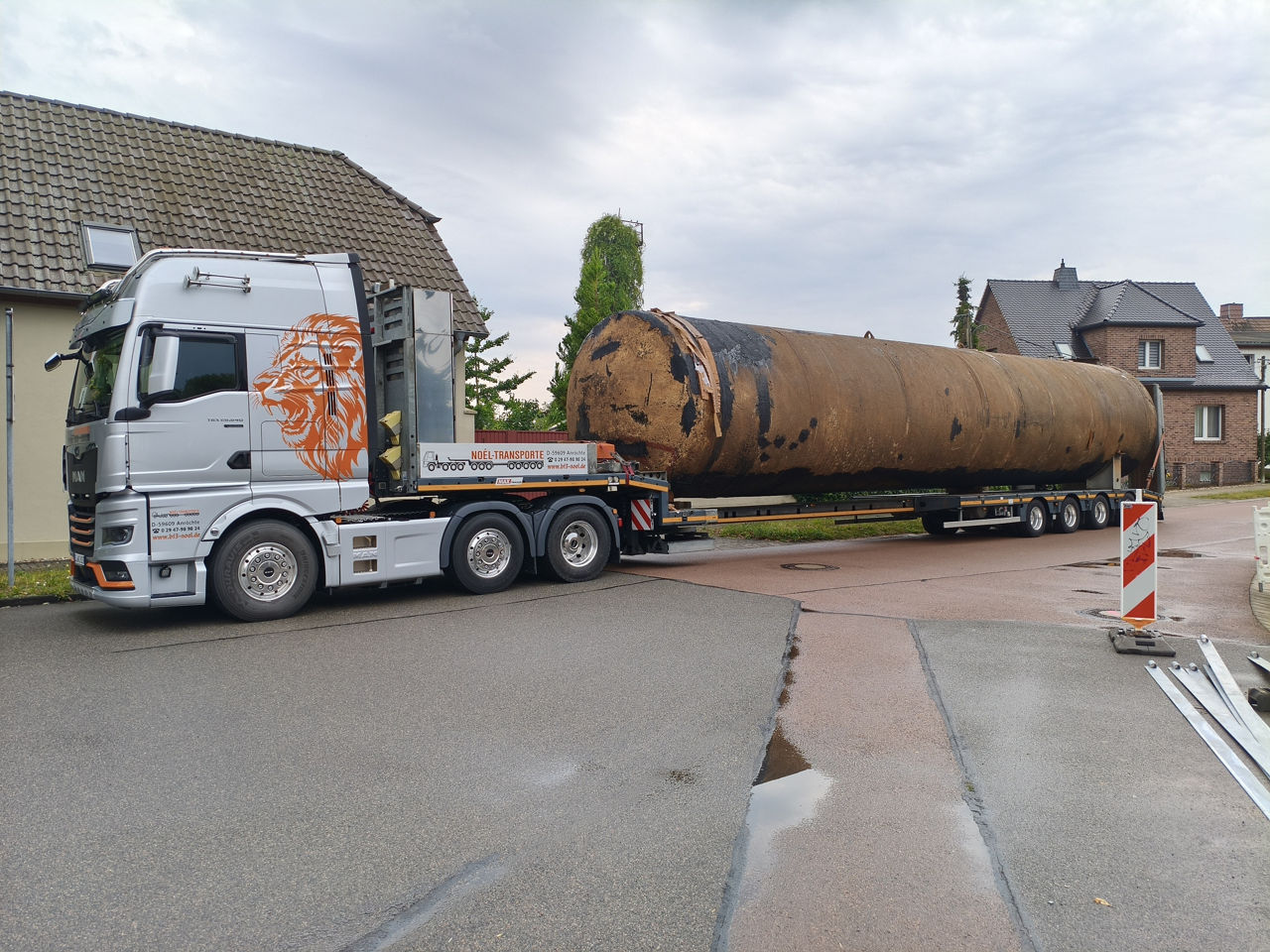 Der silberne MAN TGX transportiert ein sehr schweres, langes und altes Silo. 