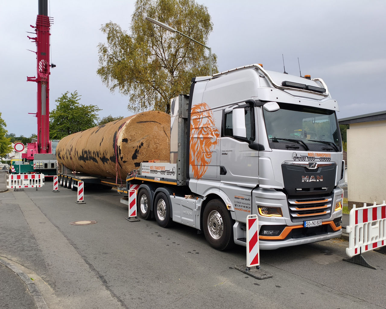 Der silberne MAN TGX transportiert ein sehr schweres, langes und altes Silo. 