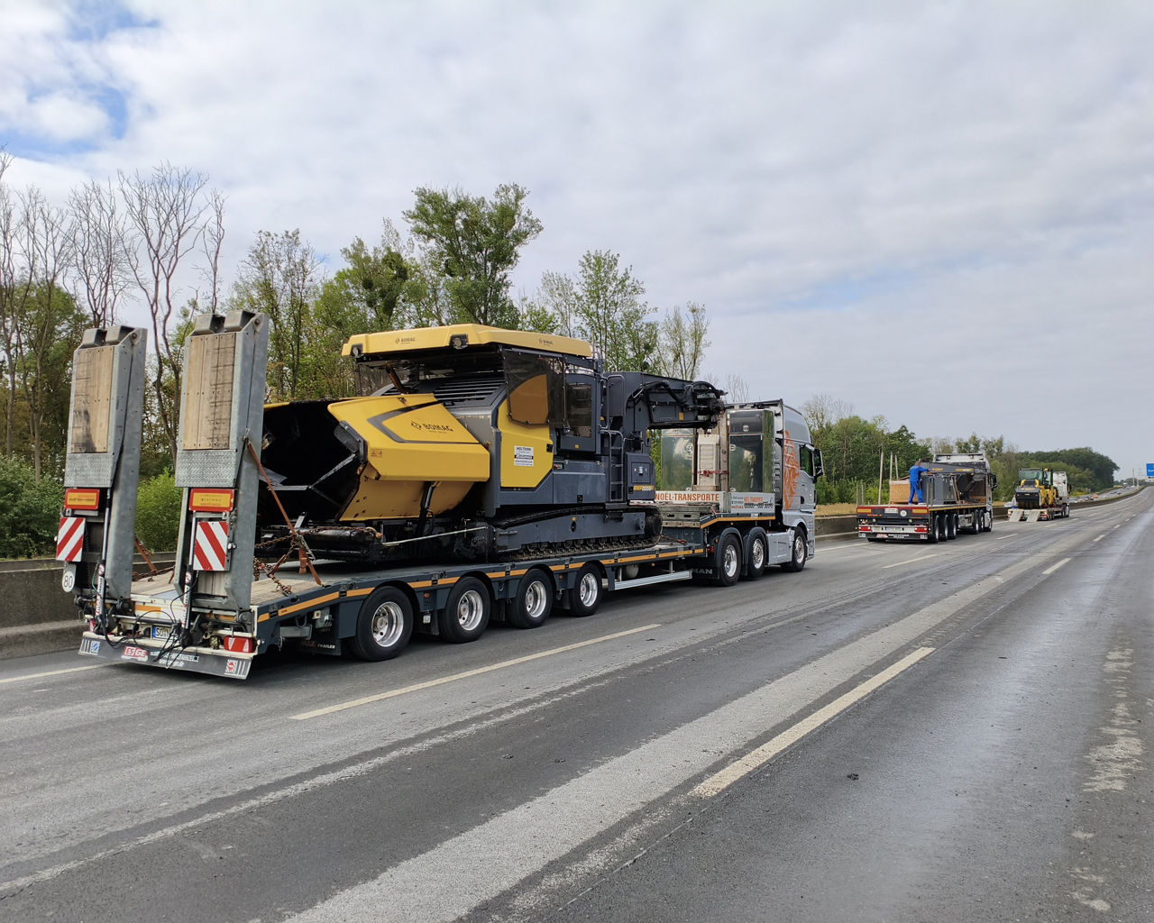 Die drei MAN TGX beliefern eine Autobahnbaustelle und transportieren einen Fertiger für den neuen Belag. 