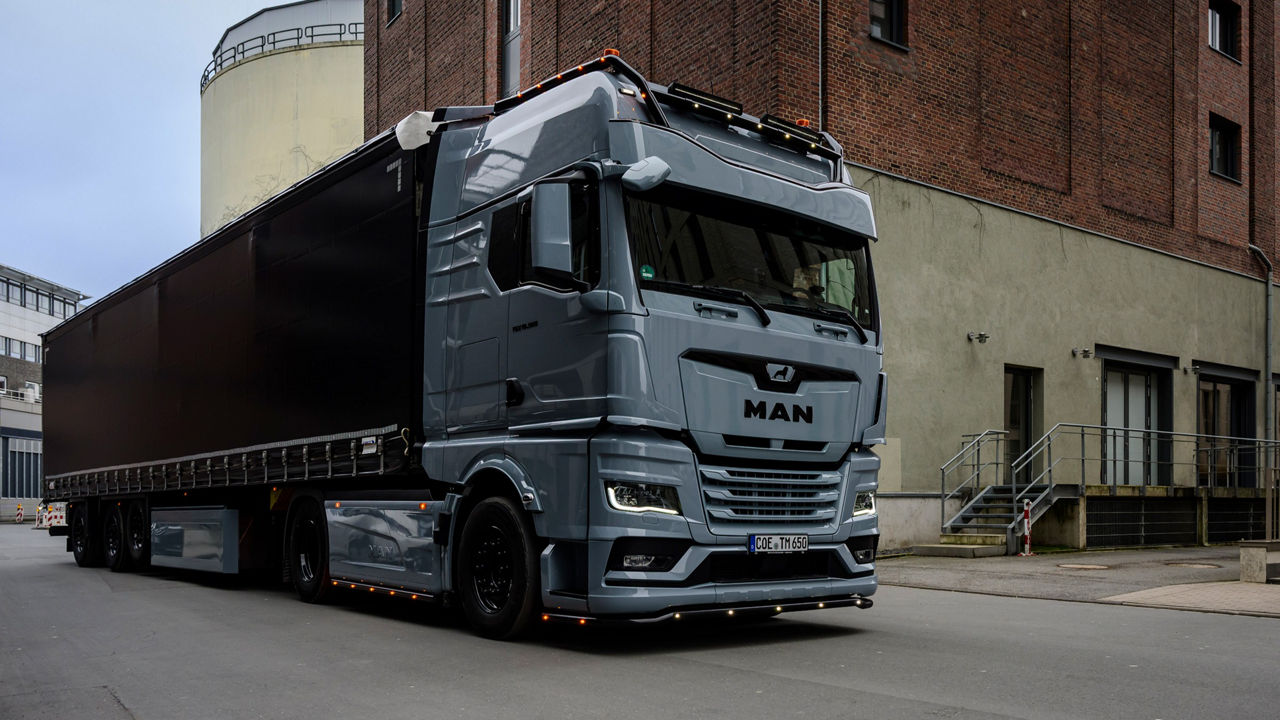 Ein grauer MAN TGX 18.560 mit D30-Motor von Tino Rateike fährt in ein altes Industrieviertel.