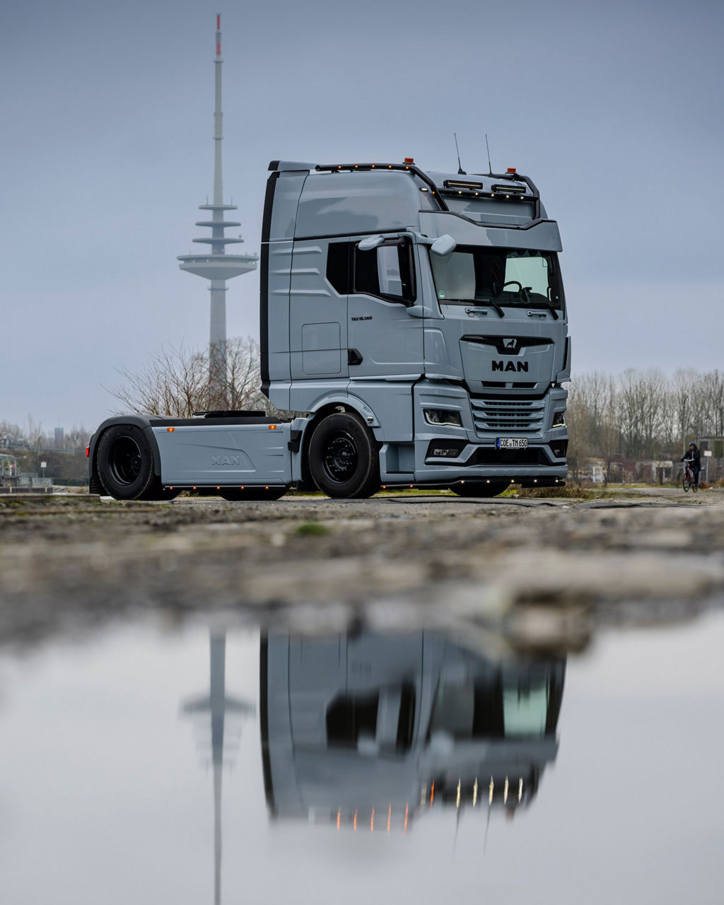 Ein grauer MAN TGX 18.560 mit D30-Motor von Tino Rateike fährt in ein altes Industrieviertel.