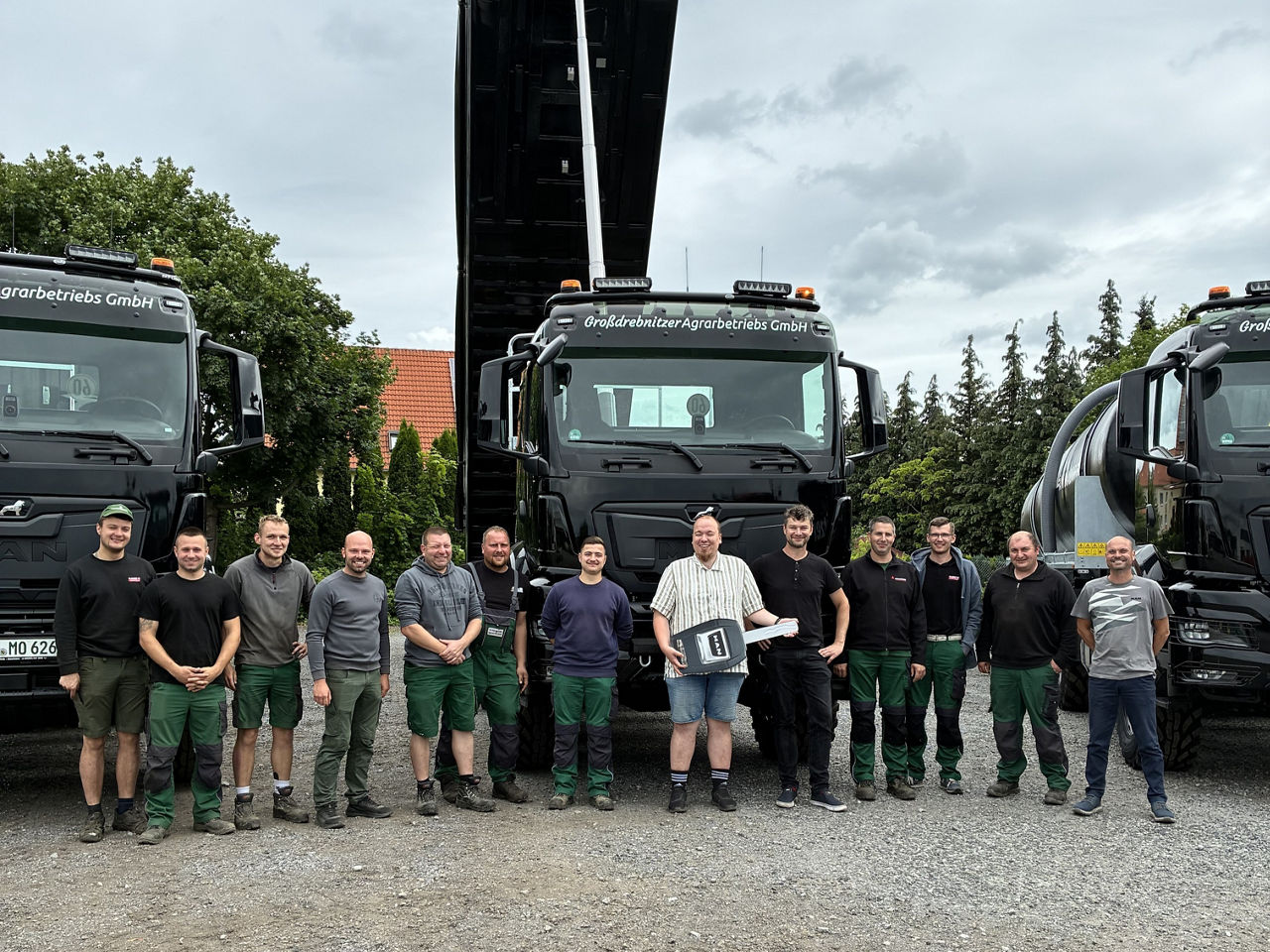Das gesamte Team der Großdrebnitzer Agrarbetriebsgesellschaft in Bischofswerda stehen vor den schwarzen MAN-Lkw. 