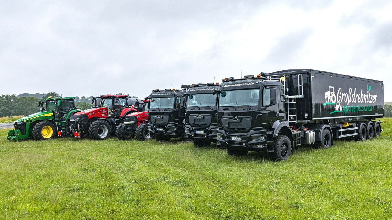 Sowohl MAN-Lkw als auch Traktoren gehören zur Flotte der Großdrebnitzer Agrarbetriebsgesellschaft in Bischofswerda. Alle Fahrzeuge stehen auf einer Wiese. 