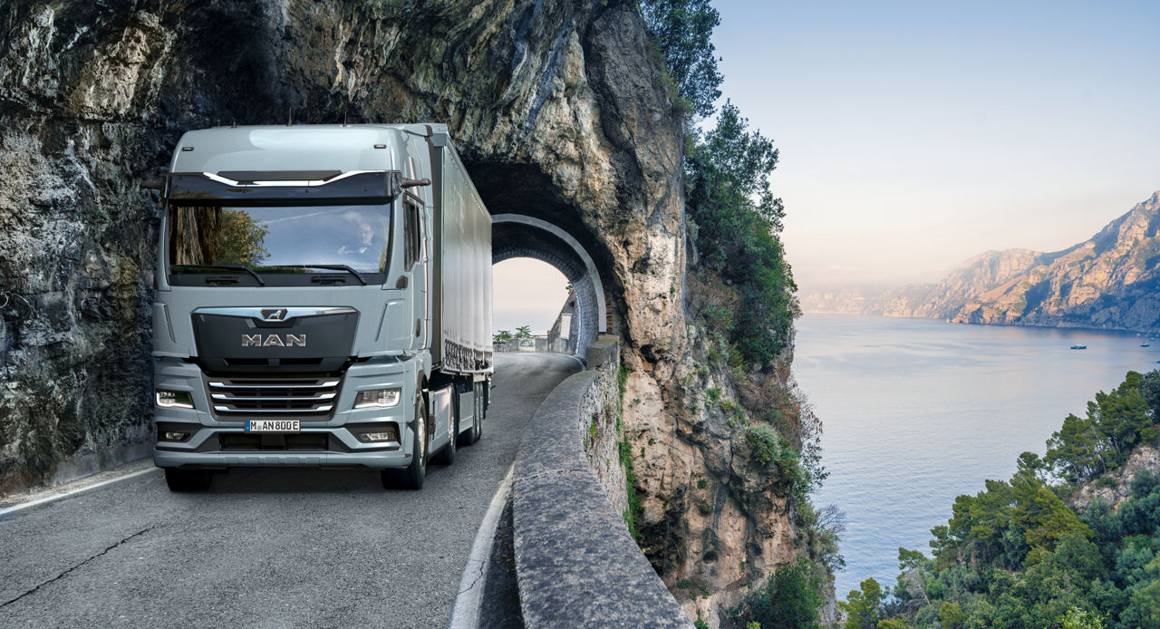 MAN Truck fährt an Küstenstraße mit Tunnel und Meerblick entlang