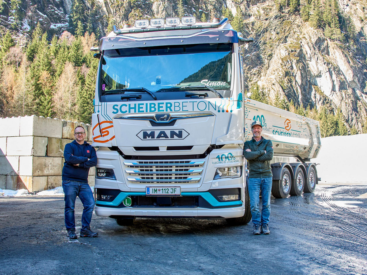 Die Besitzer der Firma Gebrüder Scheiber GmbH stehen neben ihren weißen MAN eTGX mit Kippsattel. 