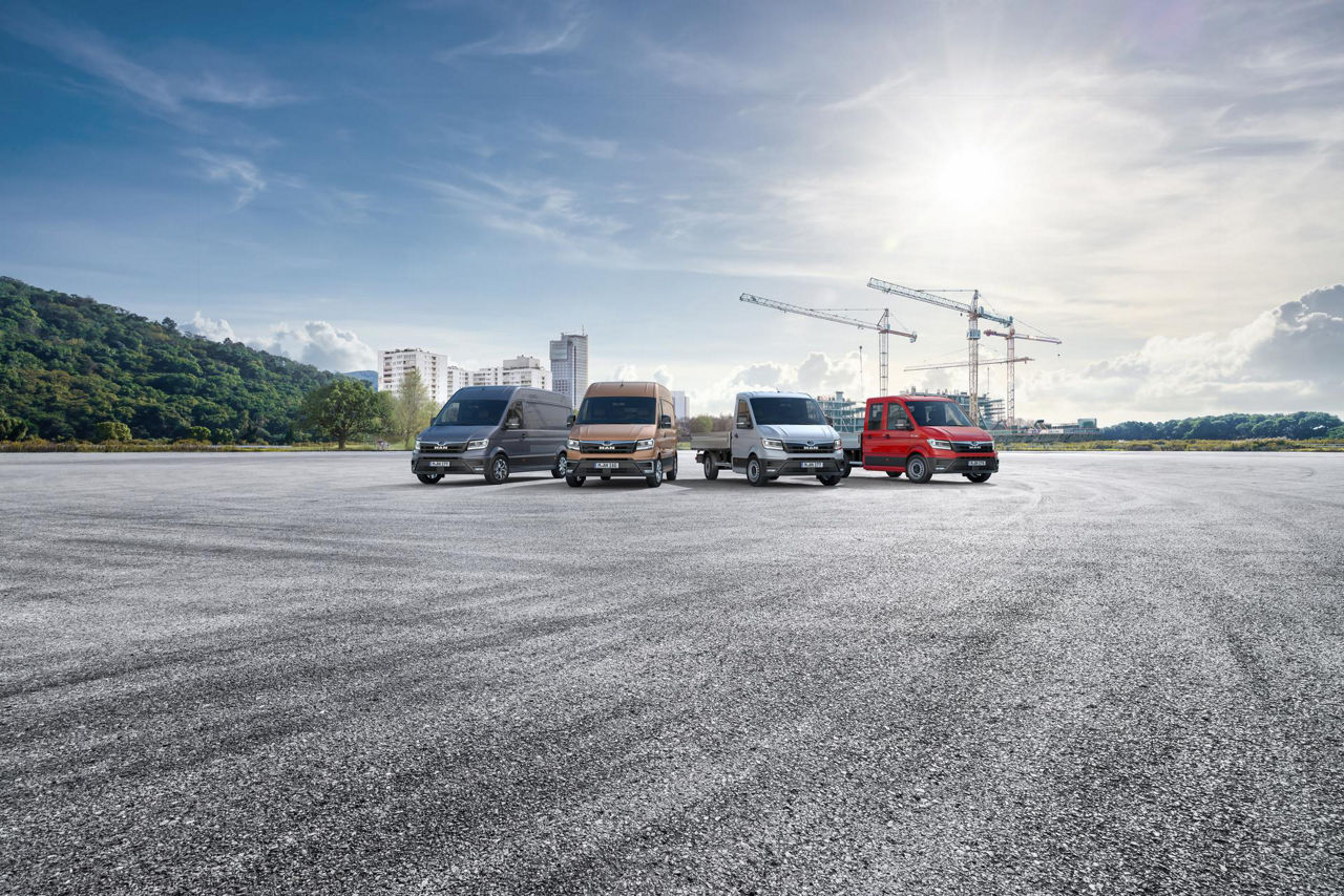 Four MAN vans parked on a wide construction lot.