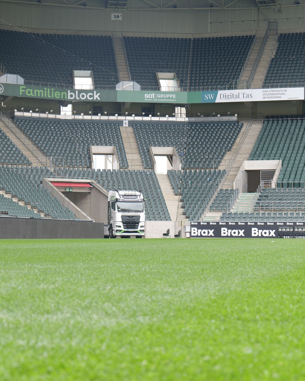 Ein weißer MAN TGX mit Borussia Mönchengladbach Beklebung und im Stadion von Borussia Mönchengladbach. Im Hintergrund sieht man die Ränge und Sitzplätze.