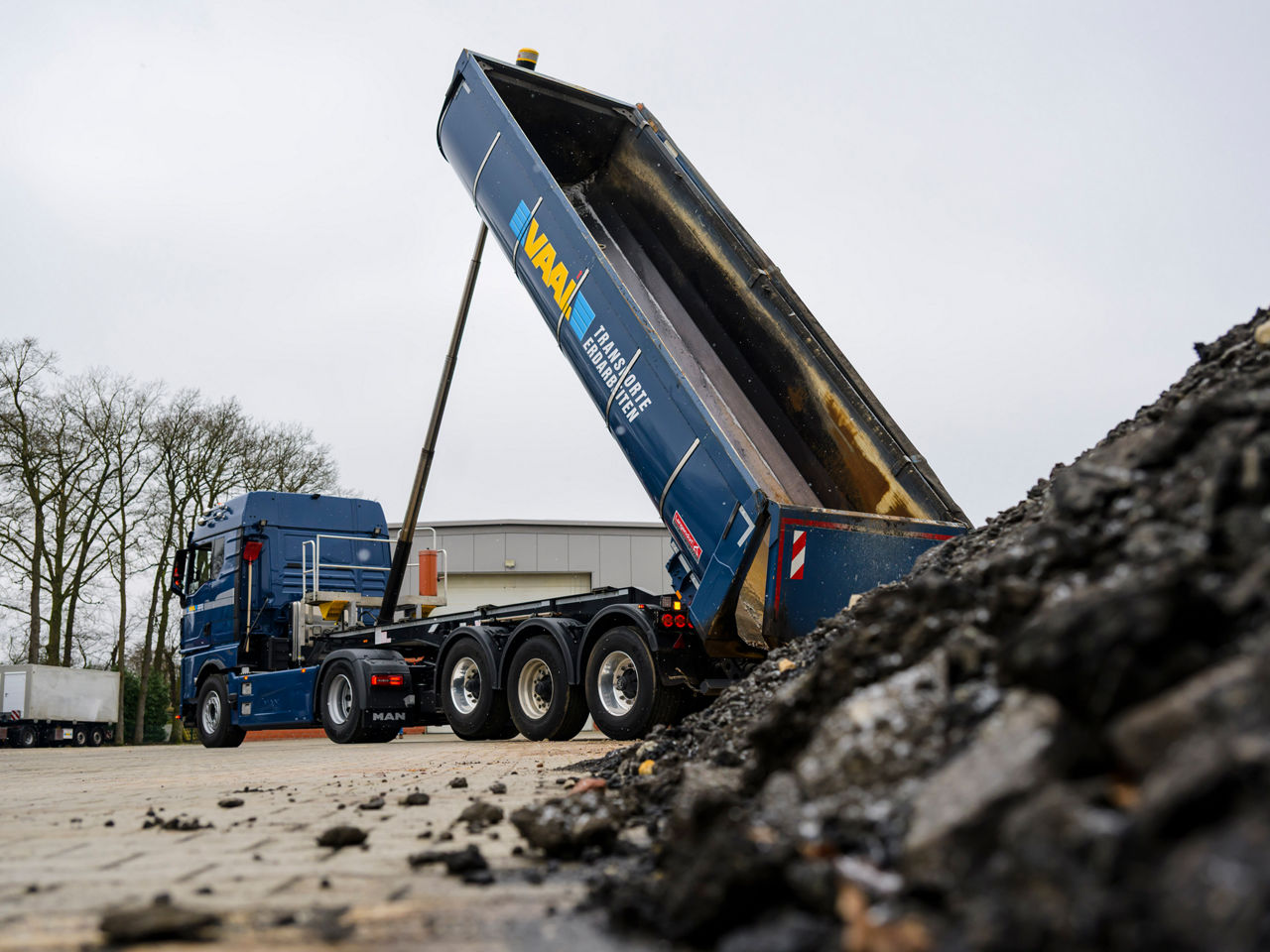Der blaue MAN eTGX von Yannik Vaal kippt gerade auf der Baustelle Material ab.