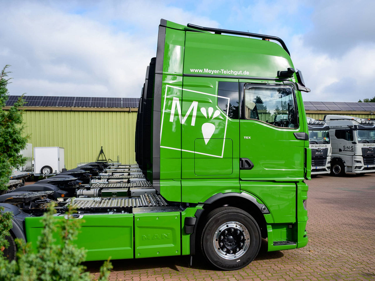 Grüner MAN TGX von der Seite mit Logo der Firma Meyer