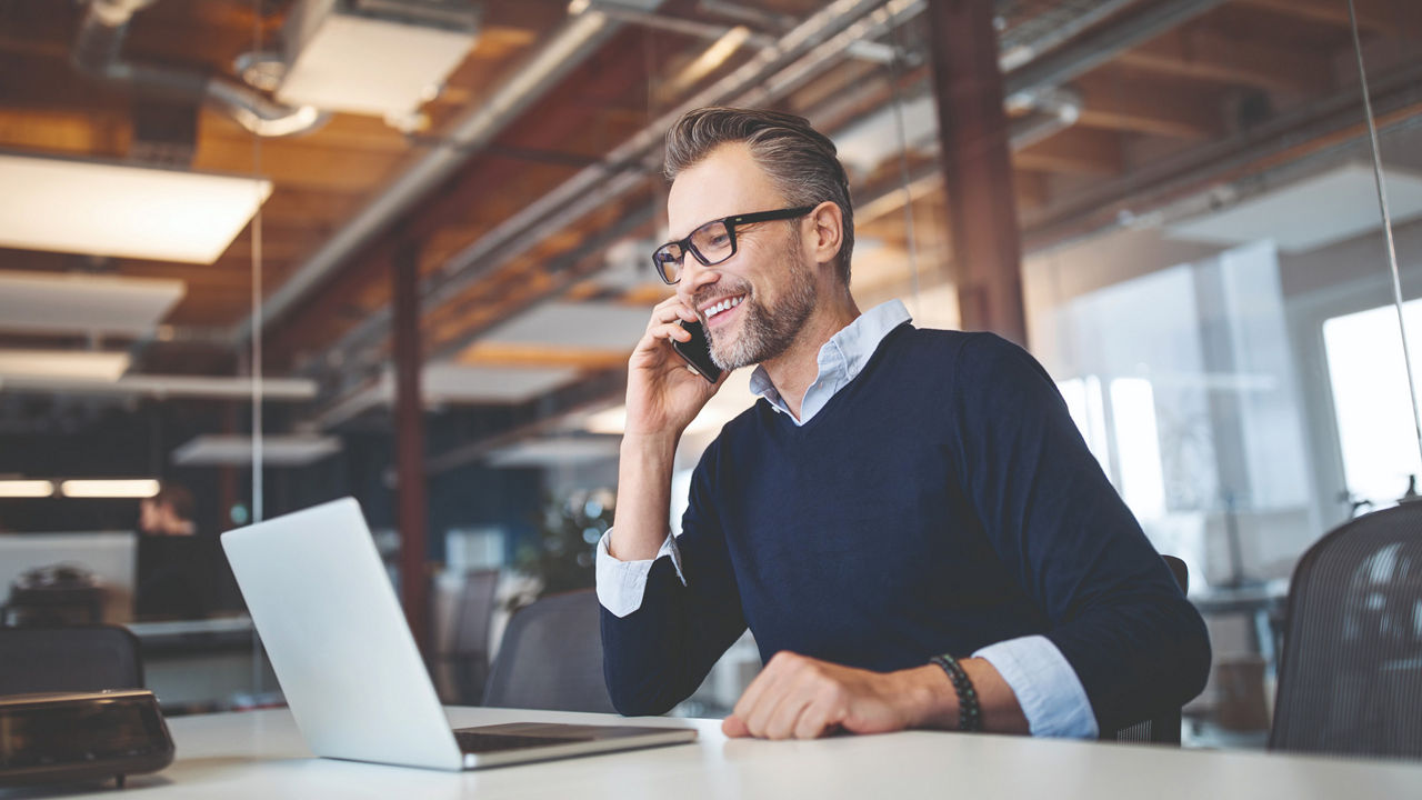 Man on the phone with laptop on the table