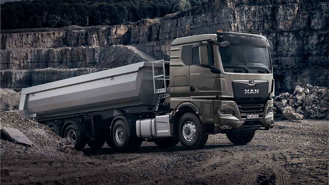 MAN truck driving up sandy incline in work area