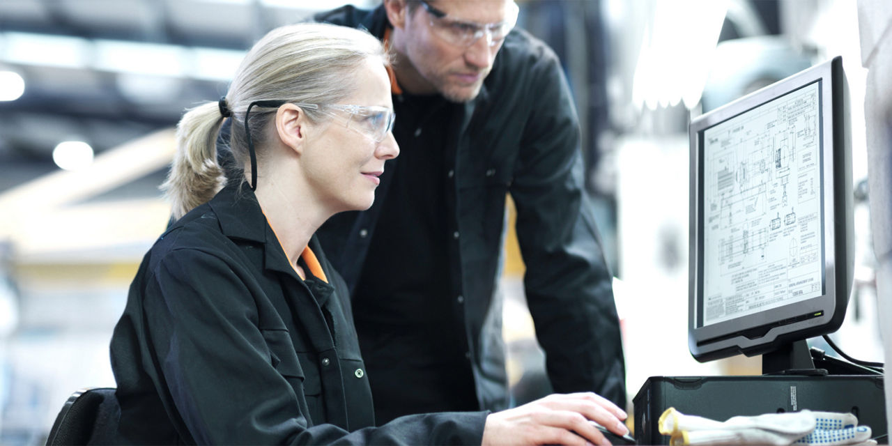 A woman and a man with protective eyewear are watching a computer monitor