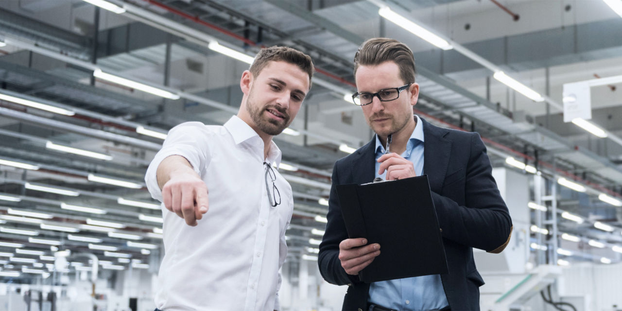 Two men standing on the shop floor pointing at something