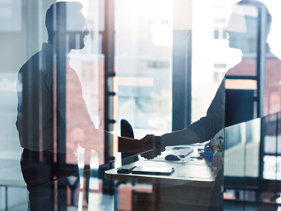 two men discussing in an office behind a pane of glass