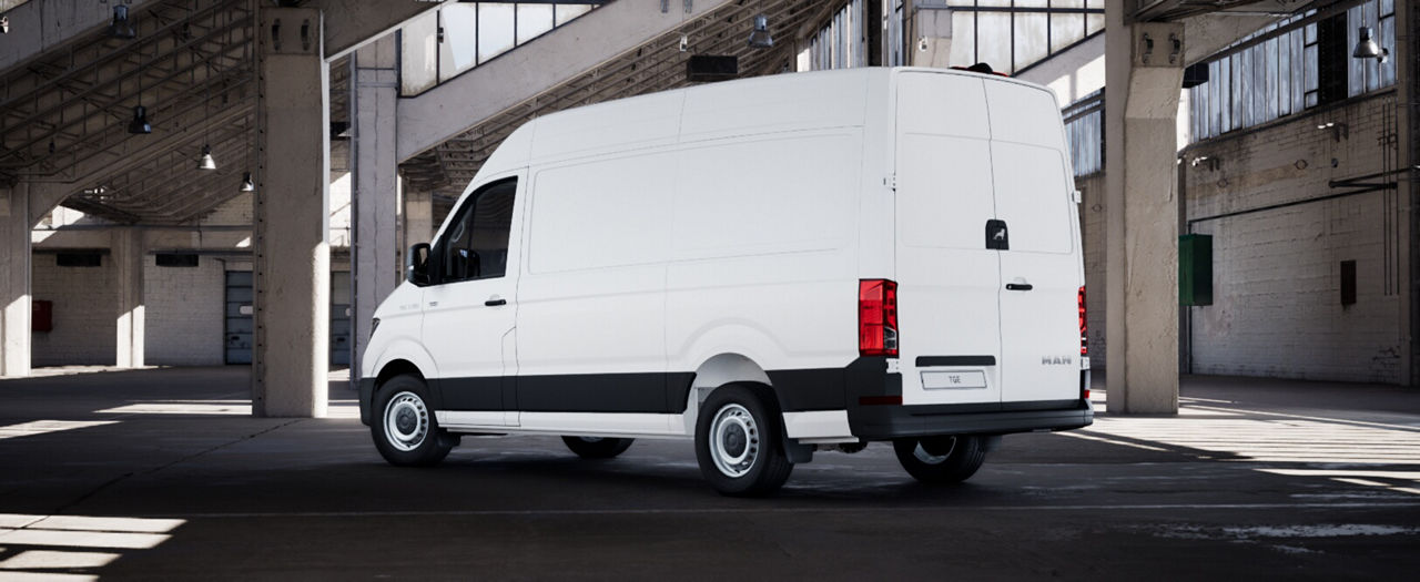 Full lright-side profile of a white MAN panel van in an industrial building