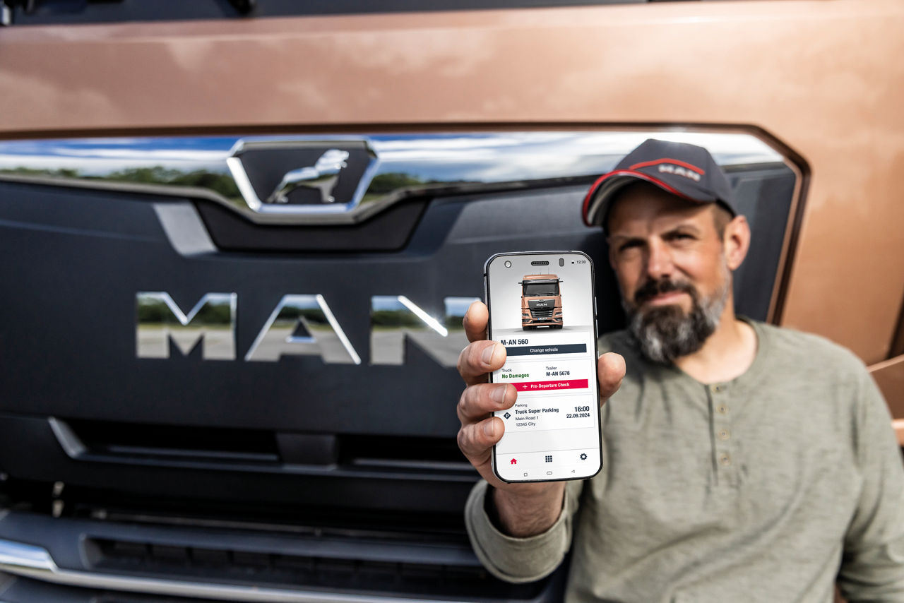 Man håller en mobil i fokus för kameran med den öppna appen i MAN Driver-appen.