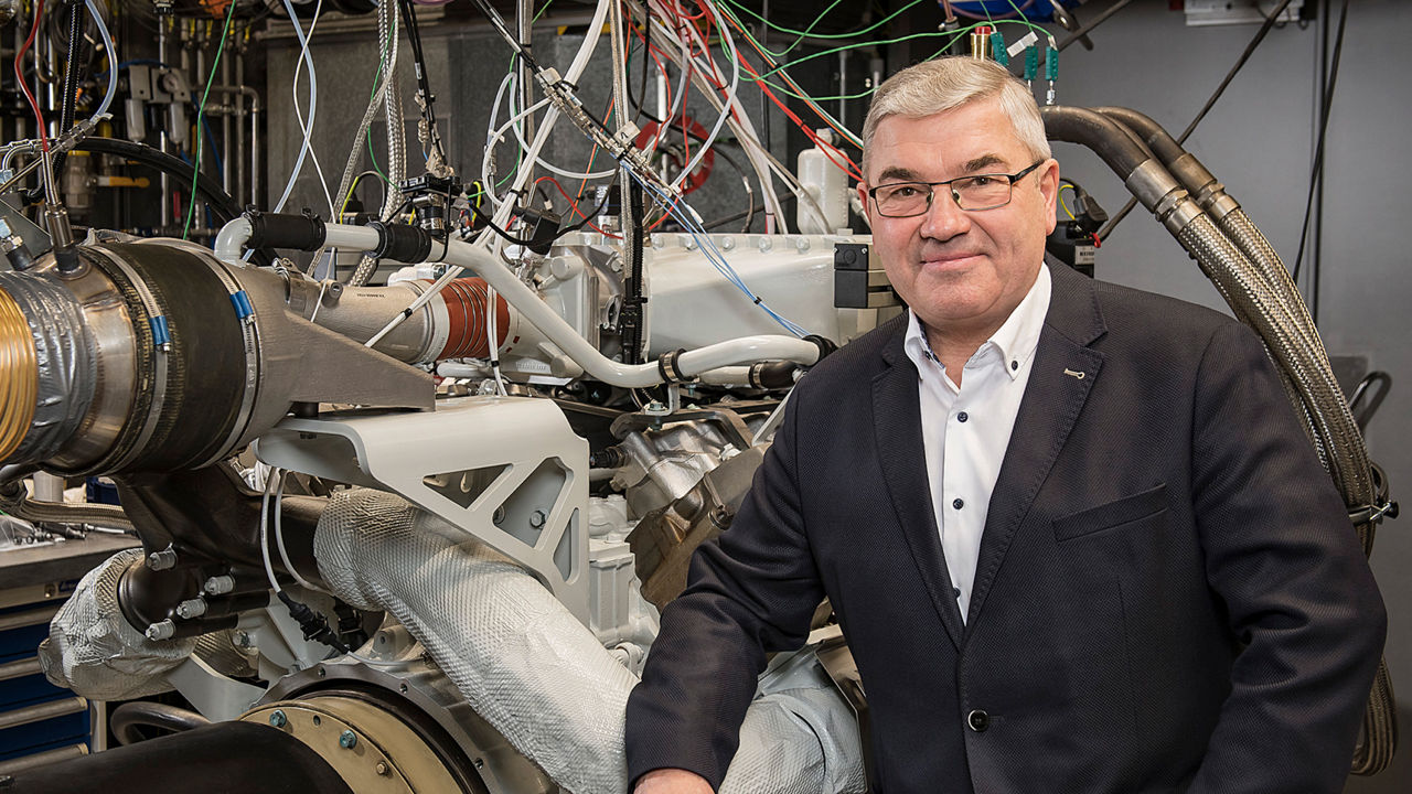 Head of Development Werner Kübler in front of a stationary hydrogen combustion engine