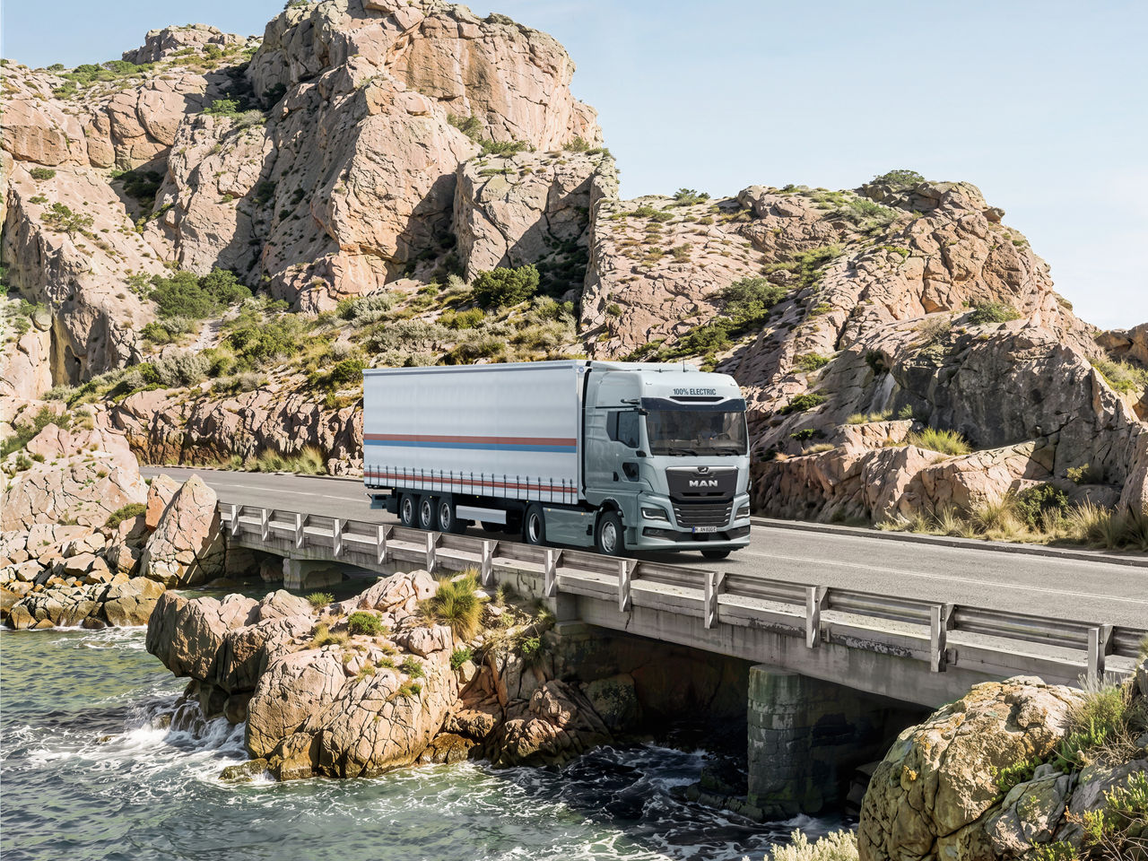 New MAN eTGX on a coastal road with rocks in the background