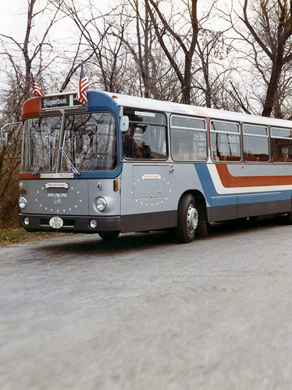 A MAN SG 192 articulated bus with US flags drives on a road in the USA
