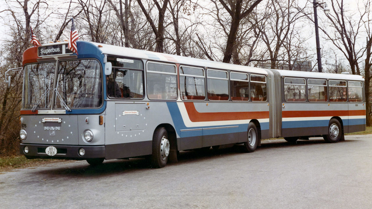 A MAN SG 192 articulated bus with US flags drives on a road in the USA