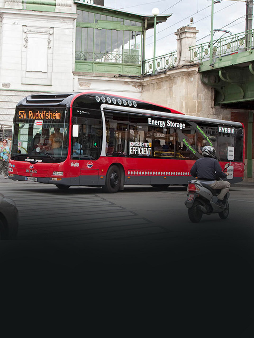 A red MAN Lion’s City hybrid bus crosses a junction