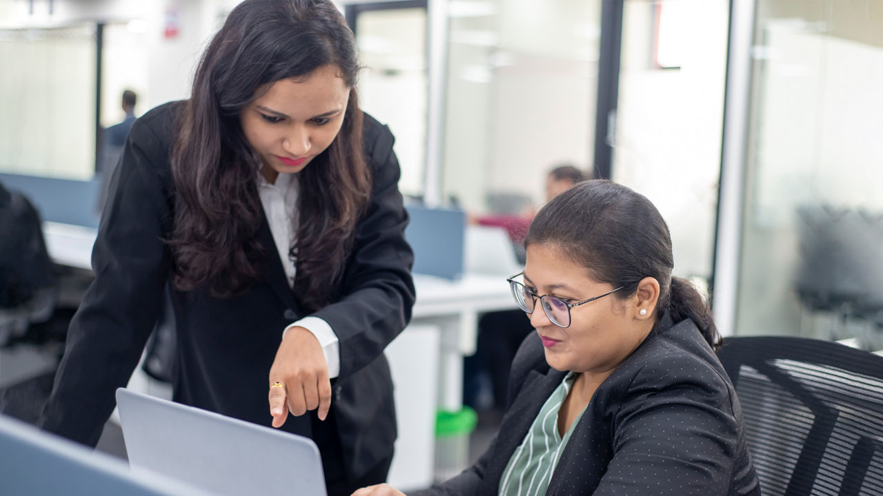 Two women stare intently at a document 