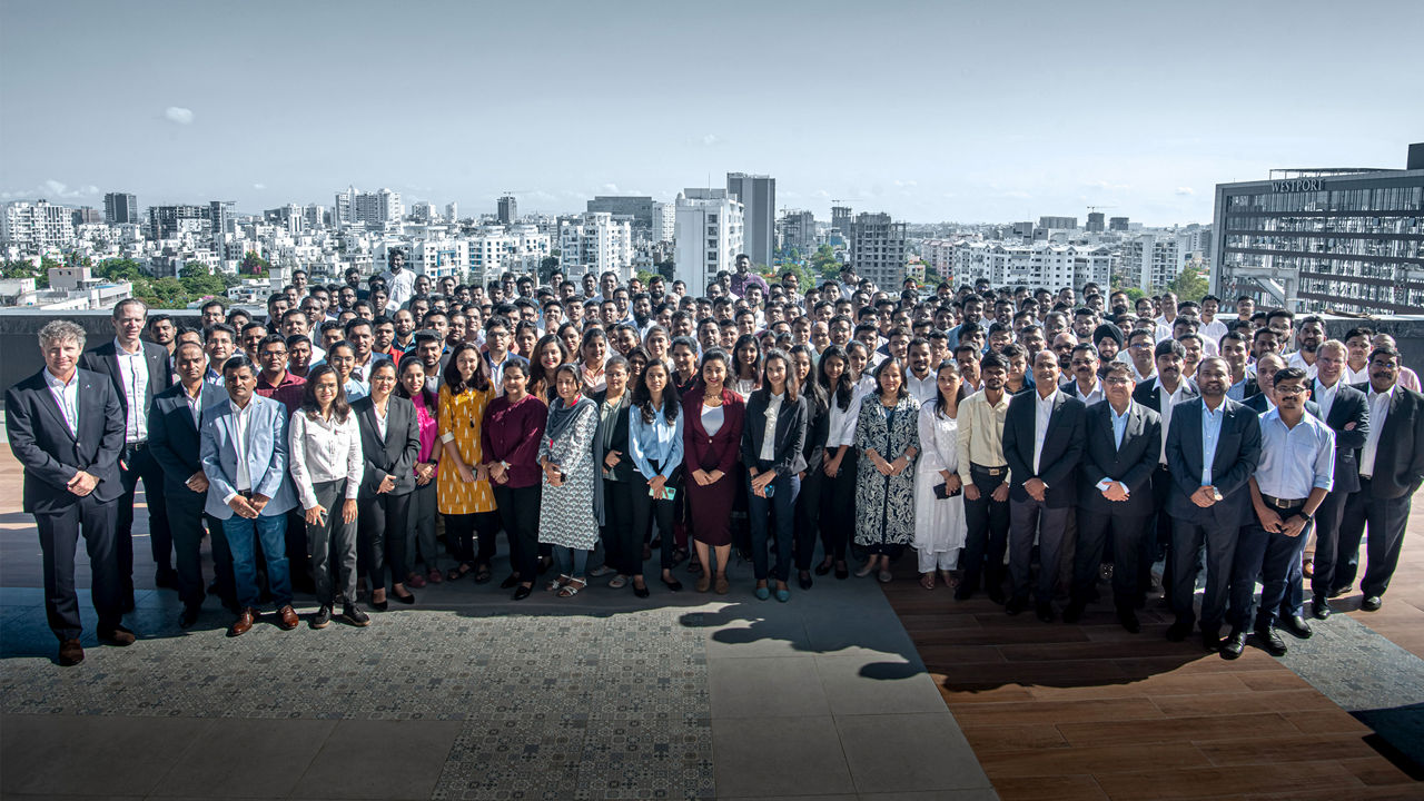 A large group of engineers stand in front of a skyline 