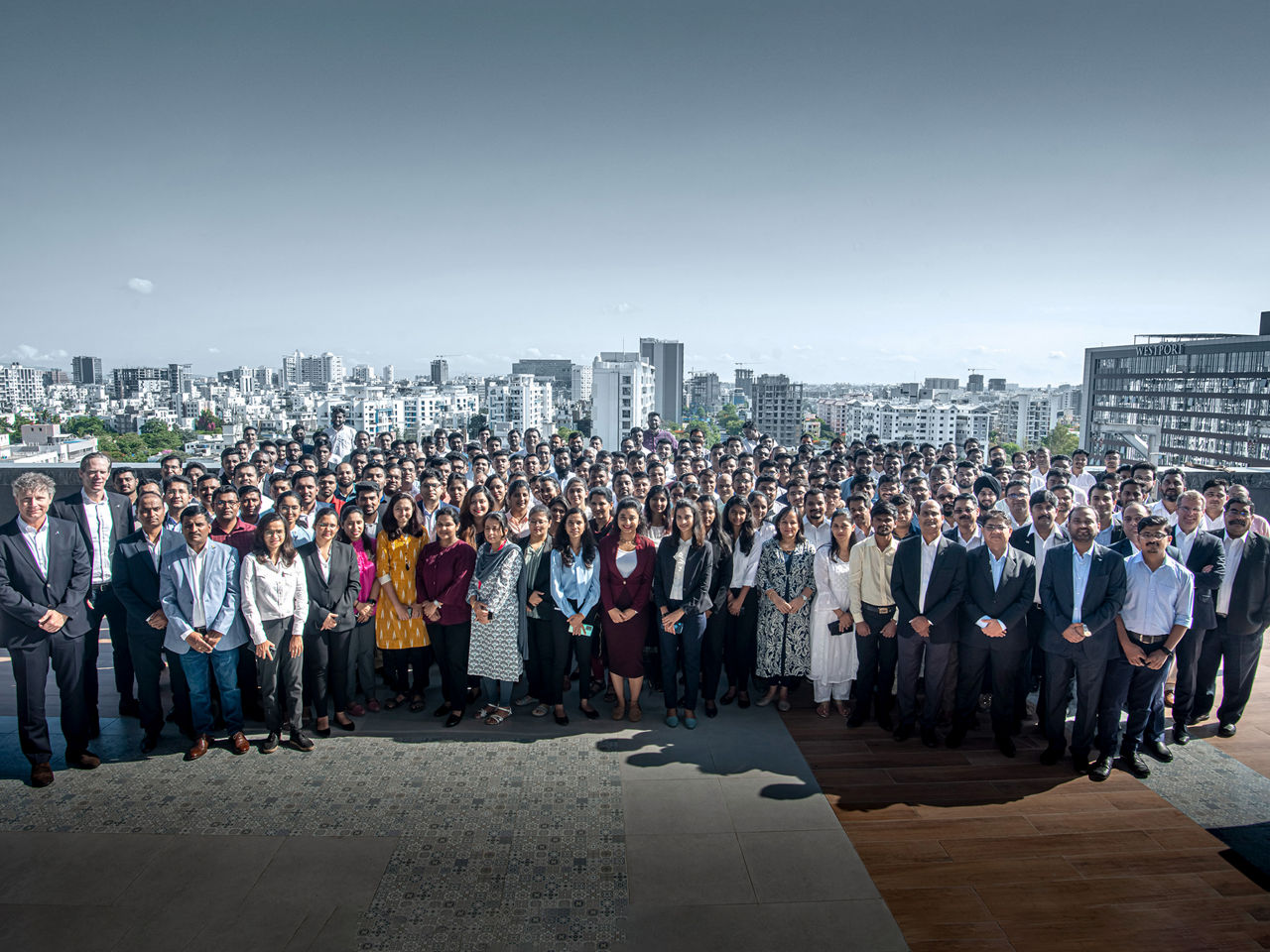 A large group of engineers stand in front of a skyline 