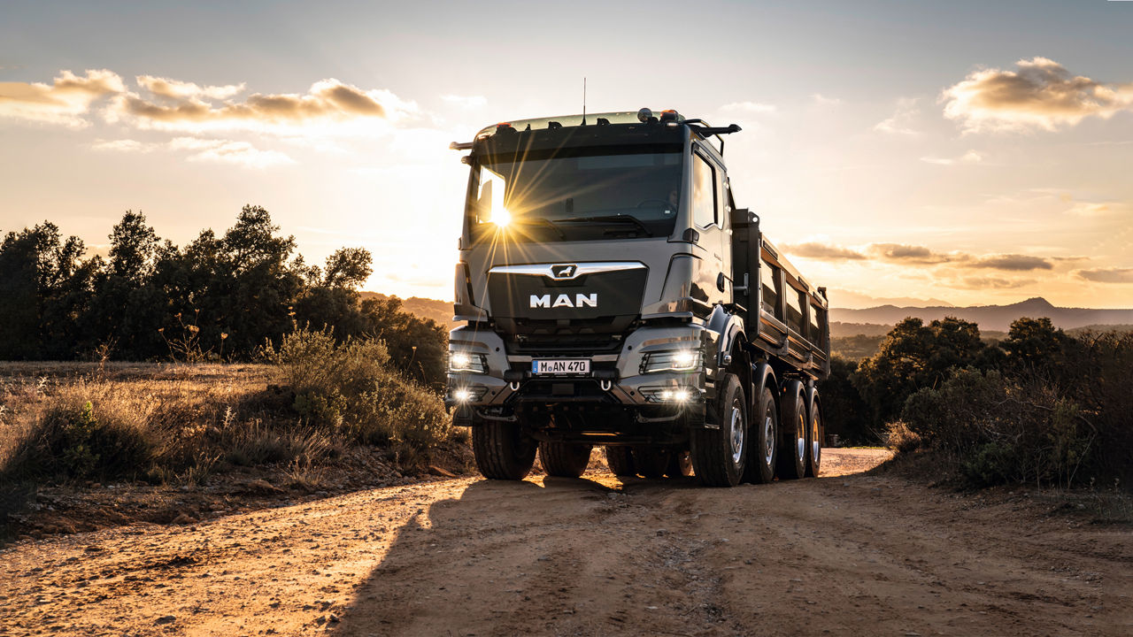 A truck on a sand hill in the sunset