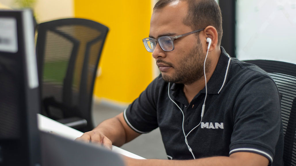 A man works at a computer and wears headphones 