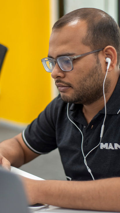 A man works at a computer and wears headphones 