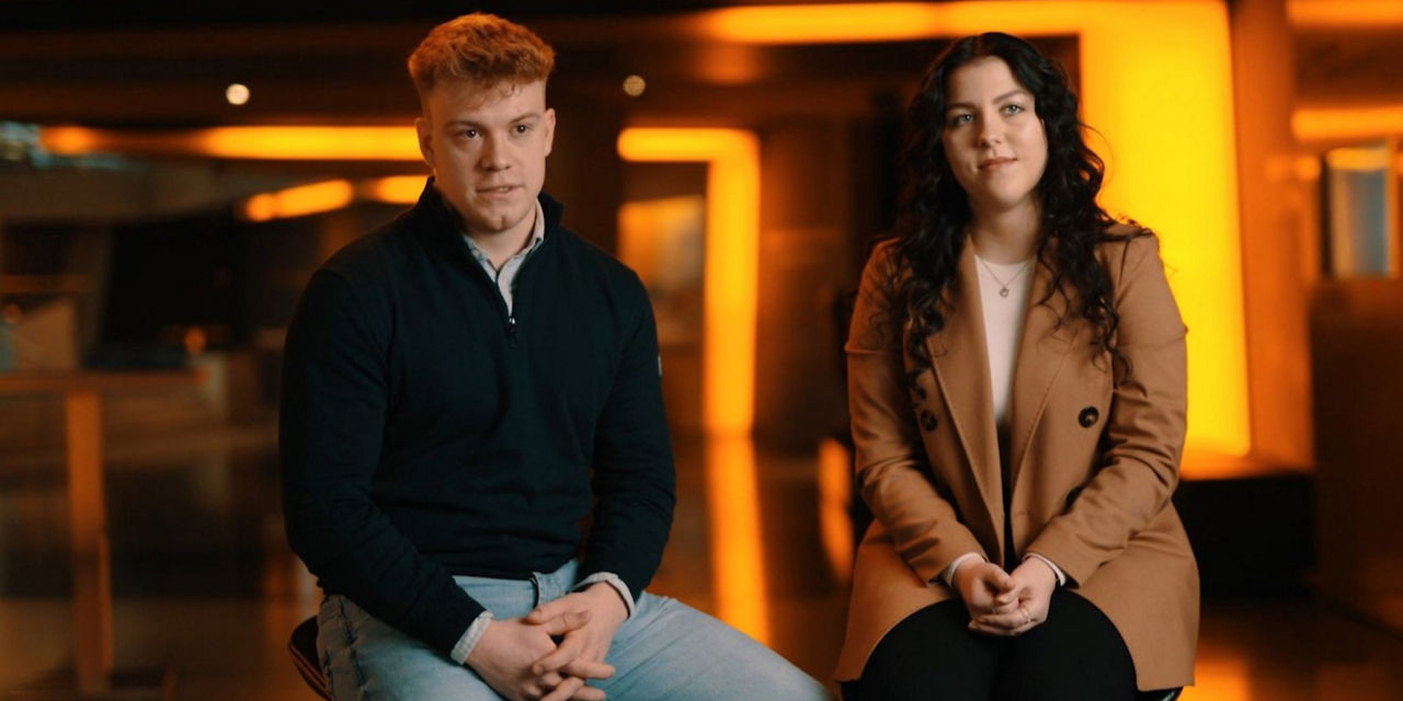 A young man and a young woman are sitting next to each other.