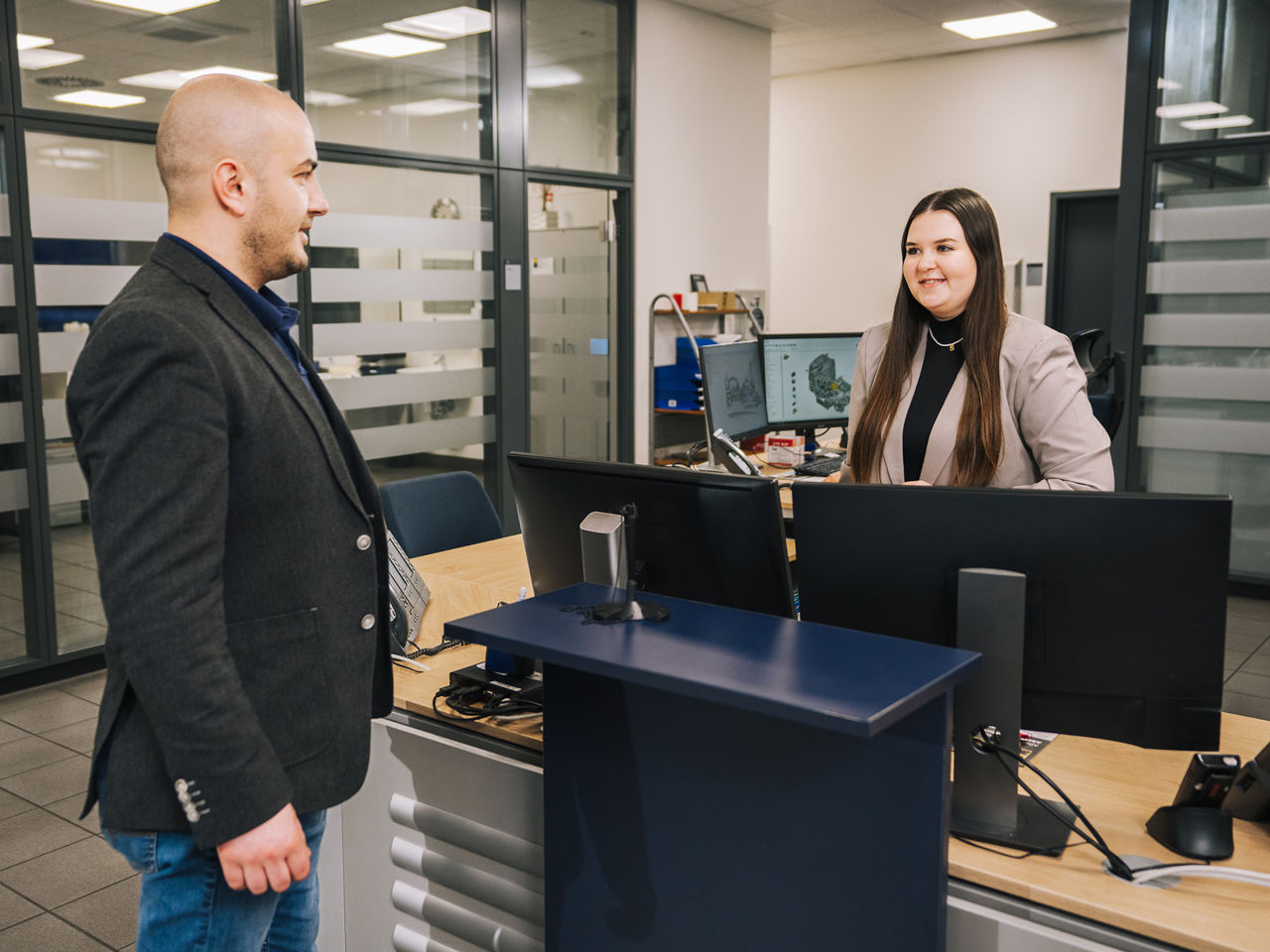 Eine junge Verkäuferin spricht mit einem Kunden.
