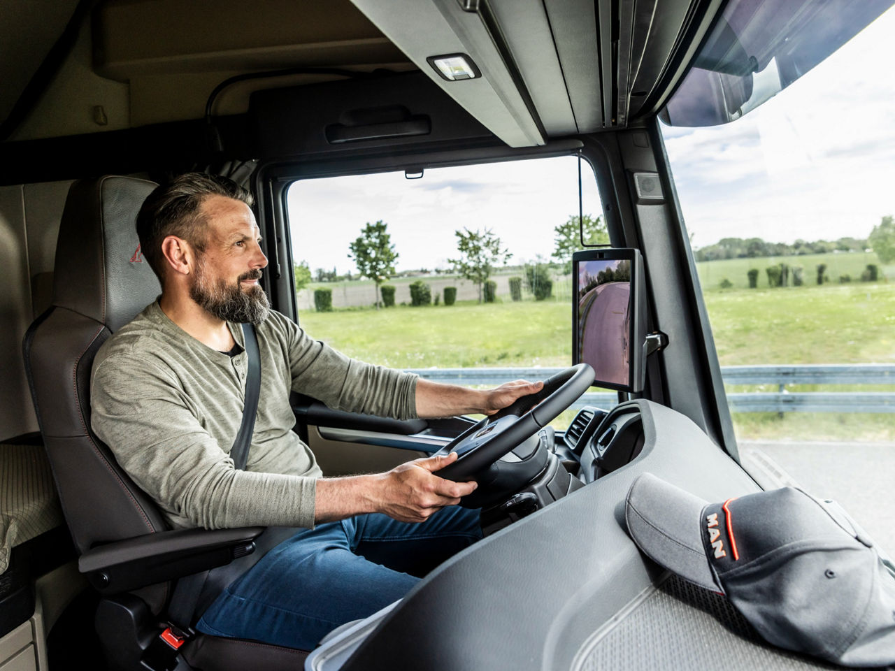 A truck driver sits behind the wheel of a modern MAN TGX