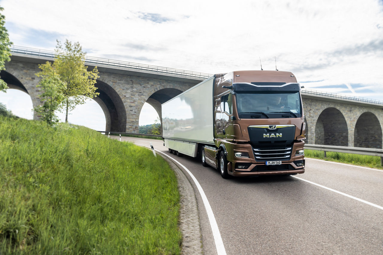Eine Fotomontage mit einem Truck, der auf einer Straße fährt und einem Mann, der auf ein Tablet schaut