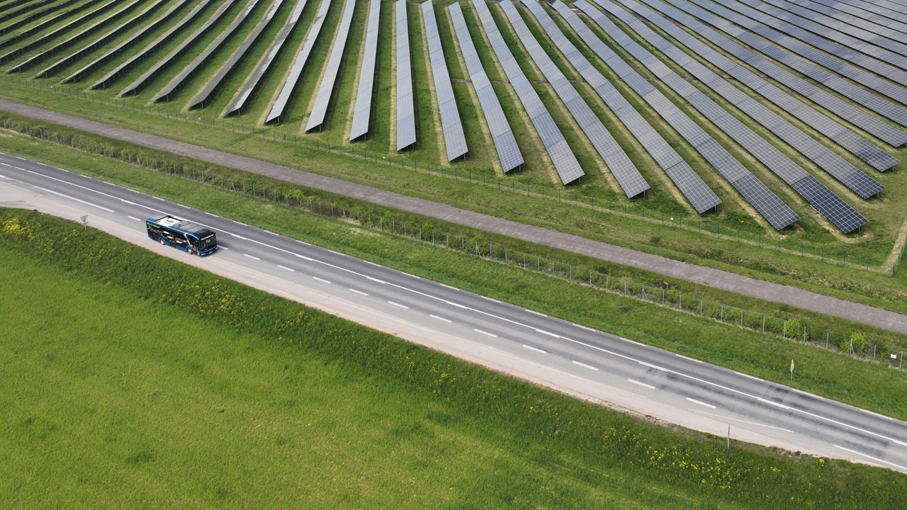 Elektrischer MAN Lion’s City E auf der Straße neben einem Solarfeld