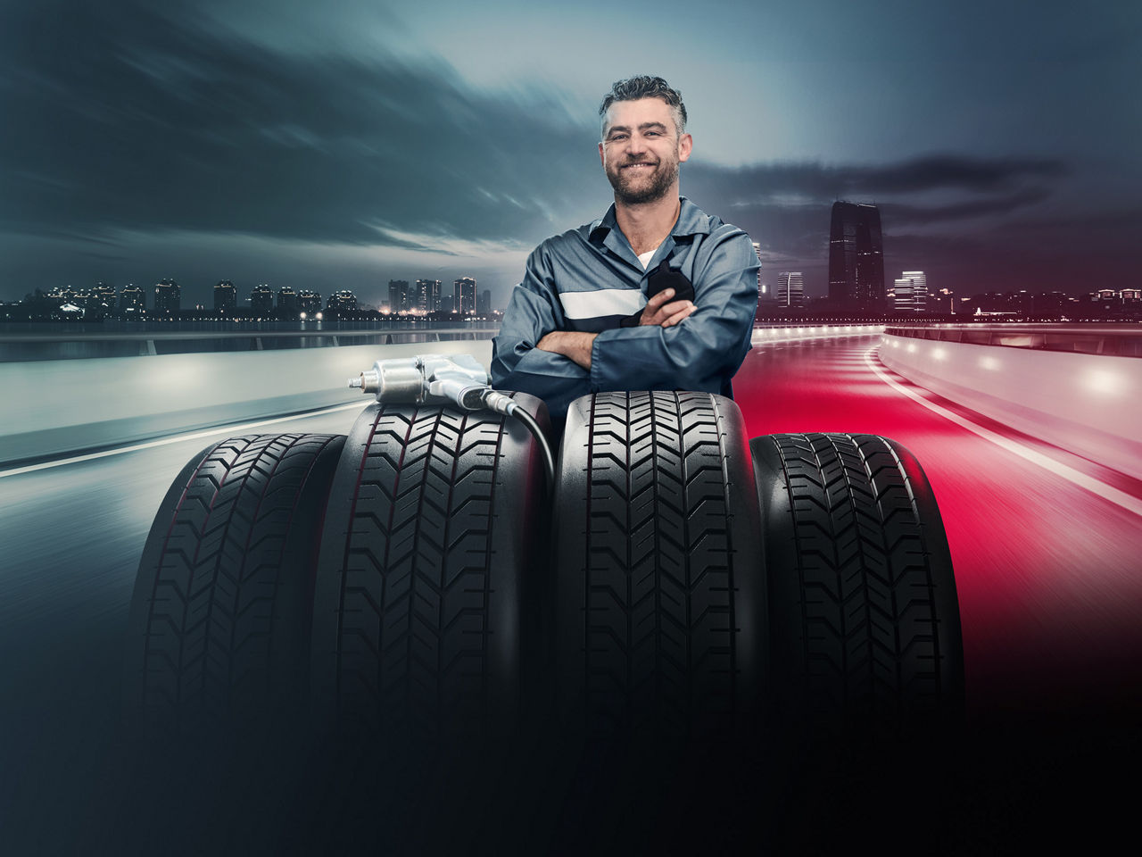 An employee from MAN Mobile24 breakdown service smiling in front of a set of tyres.