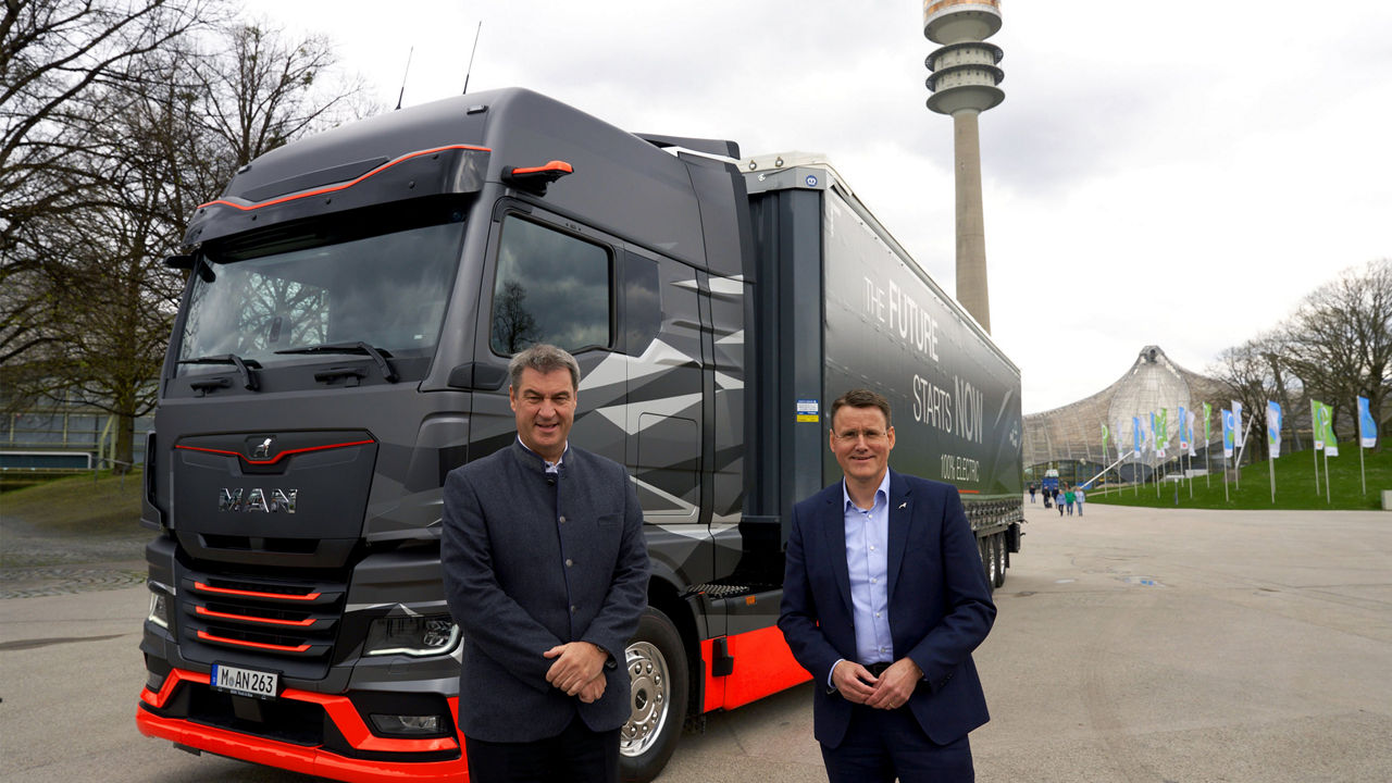 Dr Markus Söder and Alexander Vlaskamp are standing in front of a MAN truck on the Olympic grounds in Munich. 